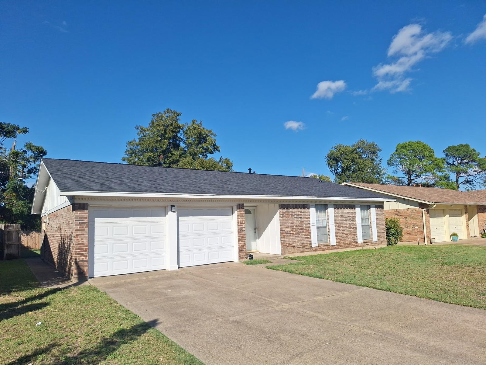 Brick home with a finished dark shingle roof